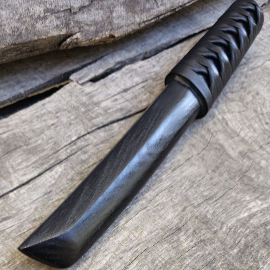 Black knife with a textured handle on a wooden surface