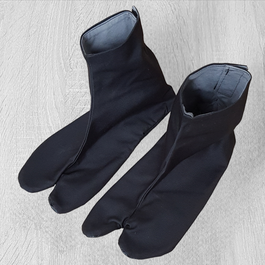 A pair of black Tabi shoes with hook and loop fastener, designed for martial arts practice on tatami.